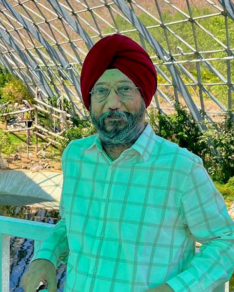 S. Rajpal Singh Mangat, wearing a maroon dastaar and a light checked shirt, standing in a glass-domed garden